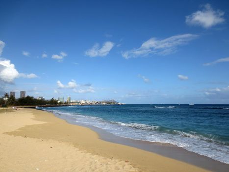 Sand Island Beach with Downtown Honolulu, Diamond head Crater in the distance on Oahu, Hawaii and waves lapping in the ocean.