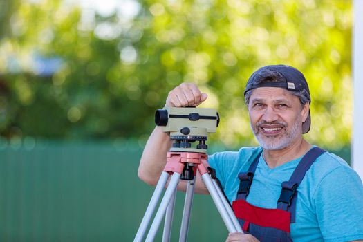 A man works with an optical level to level the landscape