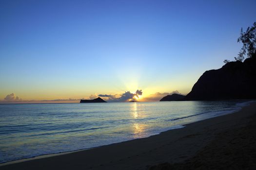 Early Morning Sunrise on Waimanalo Beach on Oahu, Hawaii over Rock Island bursting through the clouds.  January 2013.