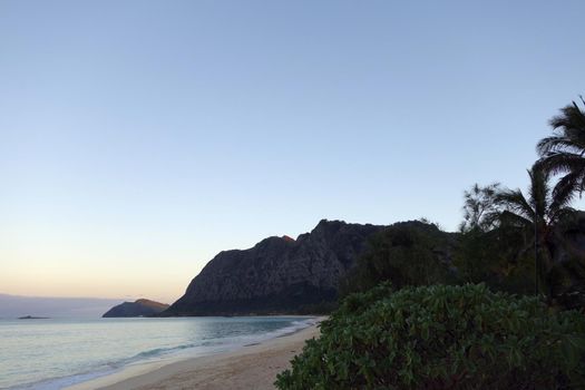 Gentle water lap on Waimanalo Beach looking towards Rock island at dusk on Oahu, Hawaii.