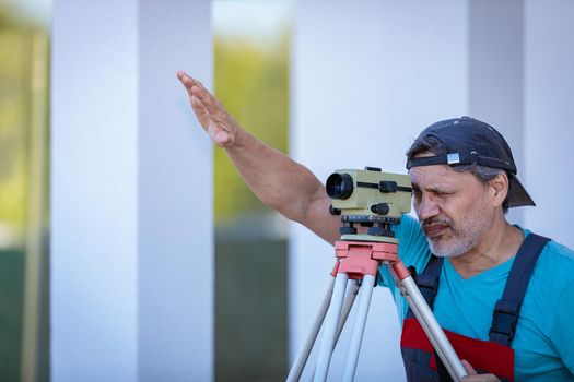A man works with an optical level to level the landscape