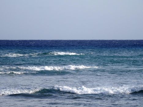 waves of the ocean break as they move towards shore in pacific ocean with a blue sky on Oahu.