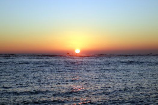 boats and buoy in the water during Sunset over the ocean at Ala Moana Beach Park on Oahu, Hawaii.