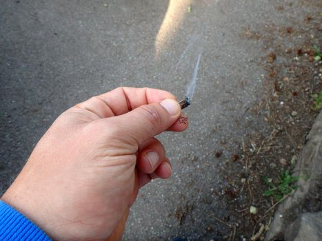 Close-up of hand smoking a marijuana pot joint featuring a three quarters smoked joint.