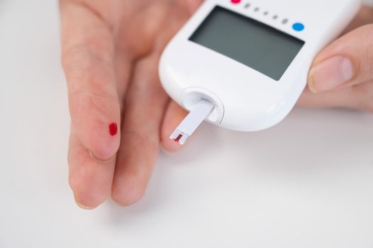 Woman measures blood sugar level with a glucometer