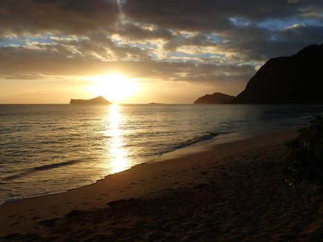 Early Morning Sunrise on Waimanalo Beach on Oahu, Hawaii over Rabbit and Rock Island bursting through the clouds.