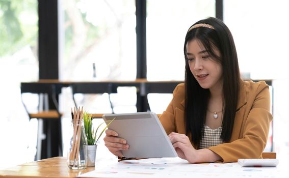 Asian attractive businesswomen using Digital Tablet standing in the office.