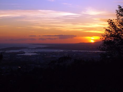 Sunset over Waianae Mountains of Oahu, Hawaii seen high up in the mountains.   Honolulu Harbor and Hawaii international airport coral runway visible.