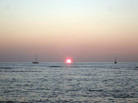 Sunset over Waikiki Ocean with boats in water on Oahu, Hawaii.  January 2015.