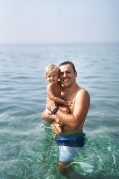 Smiling dad with little girl standing in the sea. High quality photo