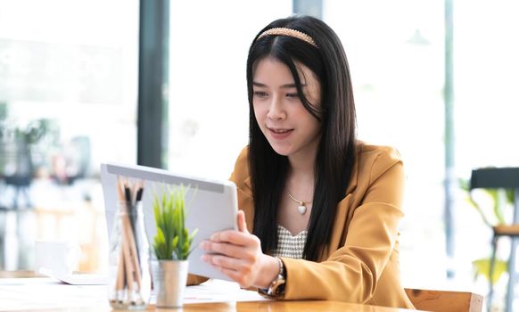 Asian attractive businesswomen using Digital Tablet standing in the office.