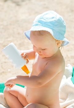 a child on the beach applies sunscreen. High quality photo