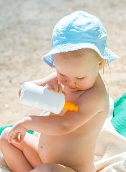 a child on the beach applies sunscreen. High quality photo