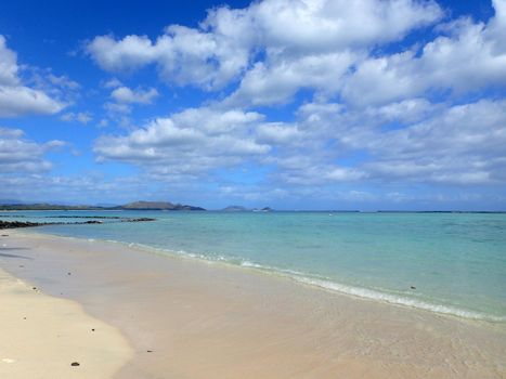 Beach next to Pahonu Pond (Ancient Hawaiian Fishpond) with Shallow wavy ocean waters of Waimanalo bay looking into the pacific ocean with a blue sky full of clouds on Windward Oahu 2015.