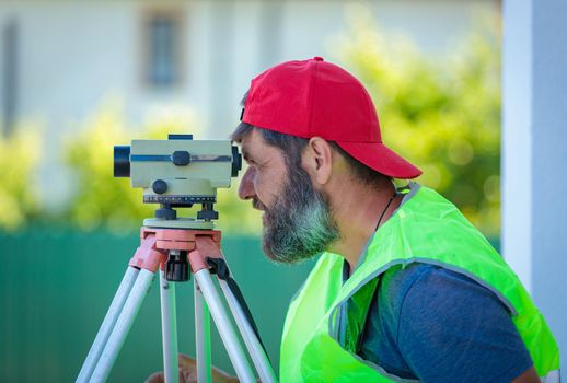 A man works with an optical level to level the landscape