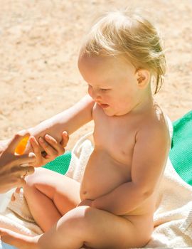 a child on the beach applies sunscreen. High quality photo