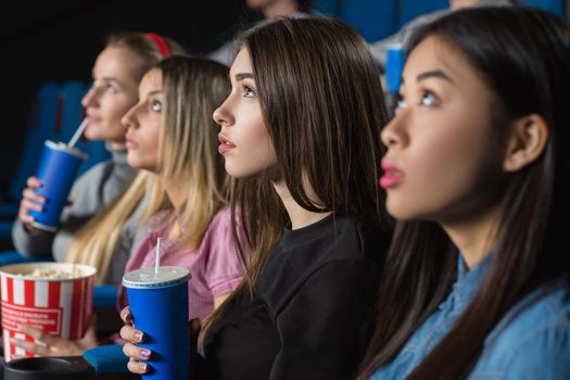 Girls night. Horizontal shot of a group of female friends watching movies together at the cinema