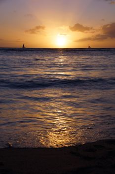 Dramatic Sunset from Waikiki beach over ocean with boats sailing on the water on Oahu, Hawaii.