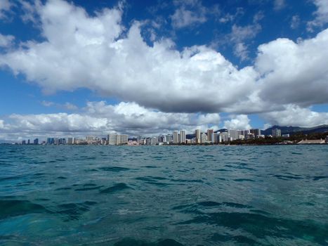 Historic Natatorium, Waikiki, Condominiums, Honolulu cityscape and San Souci Beach, coconut trees and lifeguard tower on a nice day Oahu, Hawaii seen from the water.  