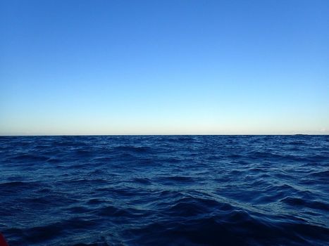 Shallow wavy ocean waters of Waimanalo bay looking into the pacific ocean with a clear blue sky on Oahu.