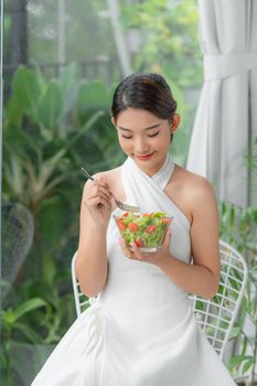 Healthy lifestyle woman eating salad smiling happy indoors on beautiful day