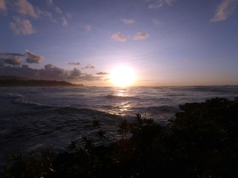 Sunset over the ocean with waves moving to shore on the North Shore of Oahu.    