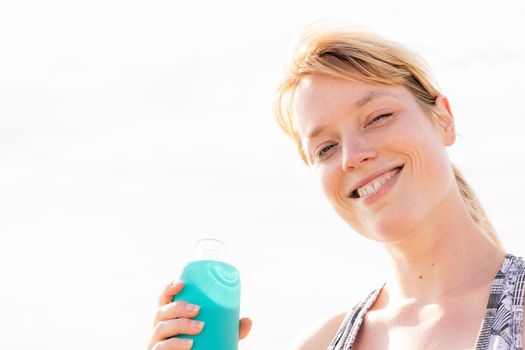 portrait of a beautiful blonde sports woman smiling with a bottle of water, concept of healthy lifestyle and sport, copy space for text