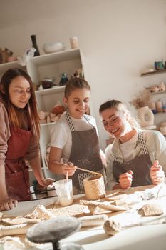 Vertical shot of a ceramist watching her students make ceramic mug