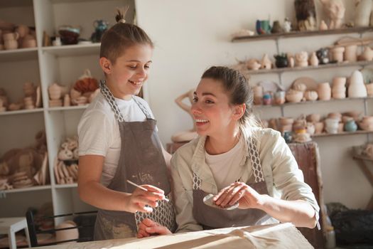 Happy young boy enjoying learning pottery with his mom at art studio