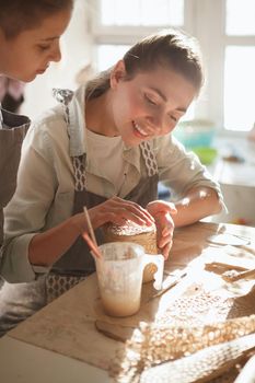 Vertical shot of a lovely cheerful woman enjoying pottery class with her young son