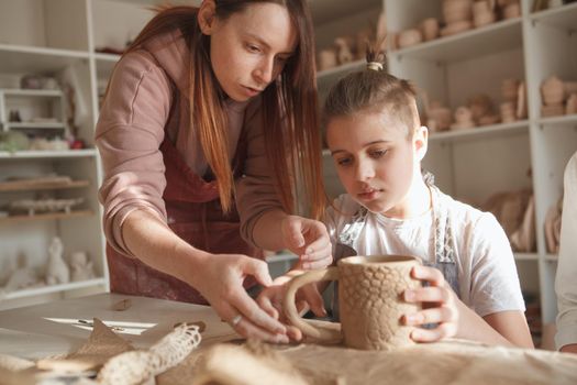 Young boy learning pottery from female ceramist