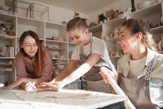 Professional ceramist teaching pottery to a young boy and his mom