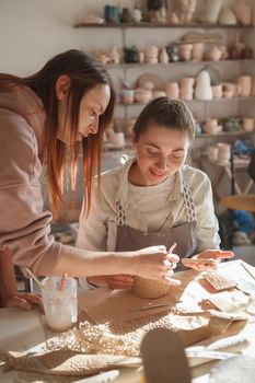 Vertical shot of a professional ceramist helping her female student making a cup