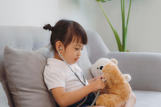 Be attentive. Pleasant pensive busy girl treating plush bear sitting on couch