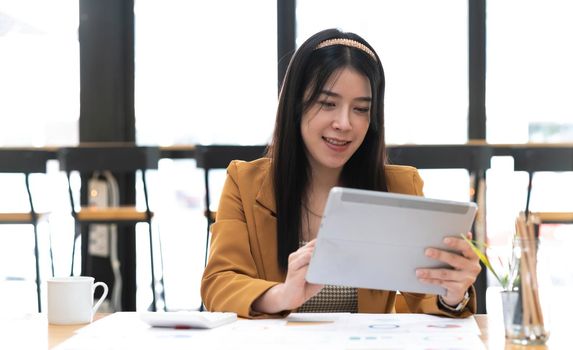 Asian attractive businesswomen using Digital Tablet standing in the office.