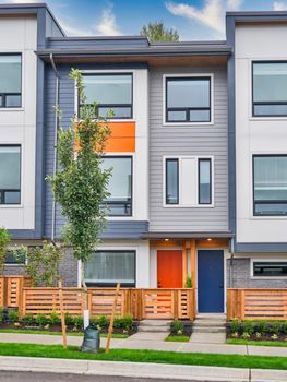 Red and blue doors of brand new residential townhouses with wooden fence in front