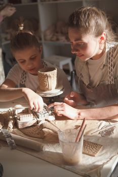 Vertical shot of a lovely boy decorating ceramics with his mom