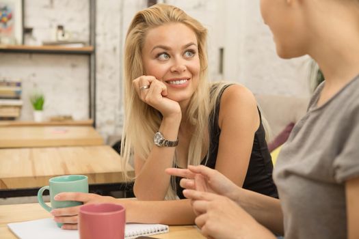 SHot of a gorgeous young woman smiling listening to her friend talking while enjoying coffee together at the cafe copyspace communication positivity lifestyle news emotions leisure campus college students