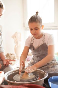 Vertical shot of a young boy throwing pot on potters wheel