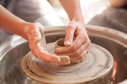 Close up of hands of unrecognizable woman shaping clay on potters wheel