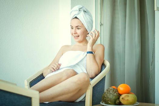 young smiling woman in the hotel talking mobile phone wearing white shower towel