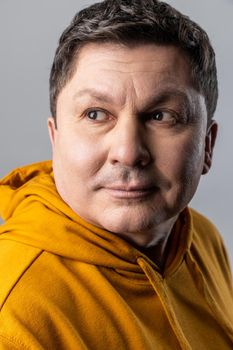 Closeup portrait of handsome confident man looking away with calm expression, male healthcare and beauty, wearing urban style hoodie. Indoor studio shot isolated on gray background.