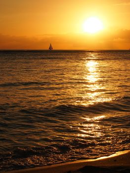 Dramatic Sunset over the clouds and reflecting on the Pacific ocean on the water with sail boat in the water off the coast of Oahu, Hawaii. April 2015.