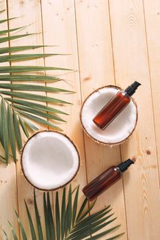 Tropical leaf, care cosmetics and coconut on a wooden table. Top view. Means for hair, body, skin. flatlay