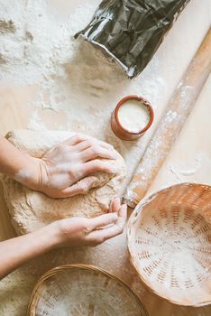 Women knead the dough from wholegrain flour and fermented yeast