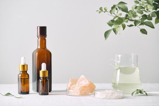 Aromatherapy. Small glass bottles with cosmetic oils. Bath salt. Fresh leaf. Objects for spa procedures on white background oil, leaf.