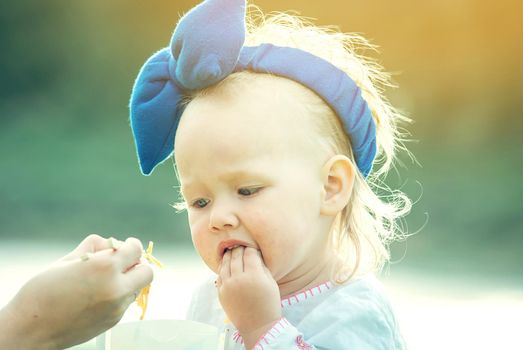 cute baby gilr is eating thai food pasta outdoor