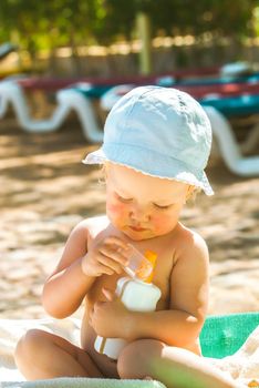 a child on the beach applies sunscreen. High quality photo