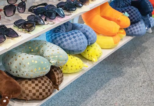 A lot of colorful inflatable and soft pillows for the convenience of the neck during travel, lie on the counter of the store, the concept of selling goods on the road.