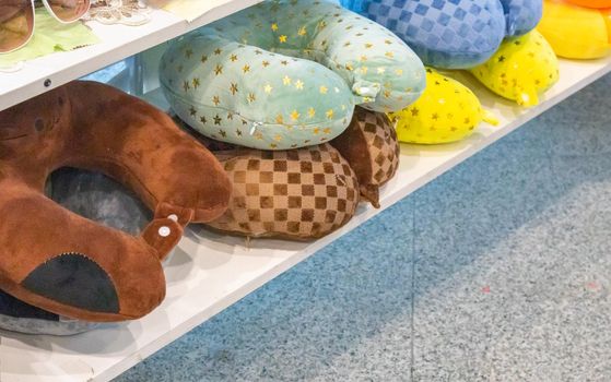 A lot of colorful inflatable and soft pillows for the convenience of the neck during travel, lie on the counter of the store, the concept of selling goods on the road.